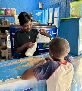 A child buying a milk-based drink at a bright blue stand.